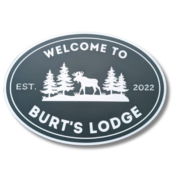 The Personalized Oval Custom Beach House Sign features Welcome to Burts Lodge, showcasing a moose and pine trees silhouette. Its dark background with white lettering reads Est. 2022, echoing the elegance of classic coastal decor.