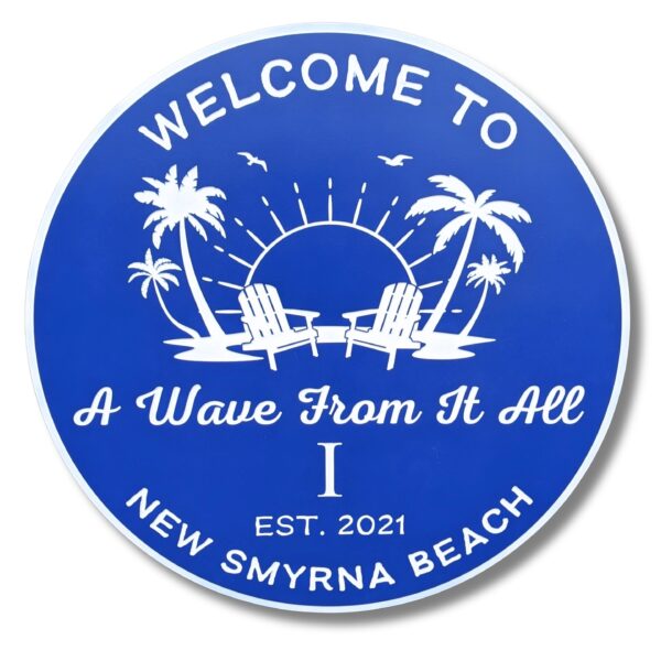 A Personalized Custom Round Beach House Sign features white graphics of palm trees, birds, sun, and two chairs on a blue background. It reads: Welcome to A Wave From It All, Est. 2021, New Smyrna Beach.