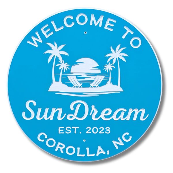 The Personalized Custom Round Beach House Sign Coastal Decor is blue with white text: Welcome to SunDream, Est. 2023, Corolla, NC. It features a beach scene with palm trees, a sunset, and two lounge chairs.