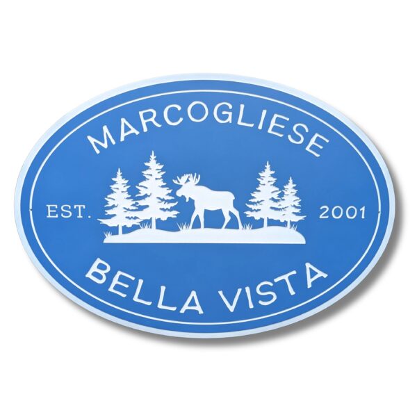 The blue oval sign with white moose and pine trees captures the charm of a beach house. It features MARCOGLIESE, BELLA VISTA, and EST. 2001. Product: Personalized Oval Custom Beach House Signs Coastal Decor.