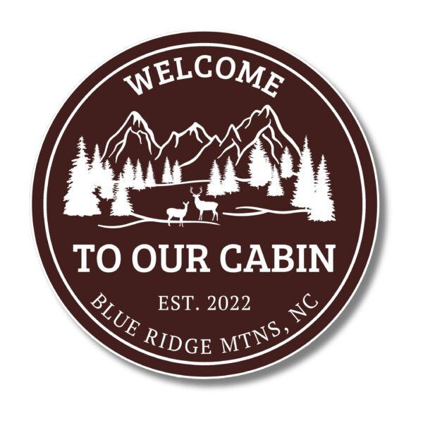 A circular sign with a dark brown background showcases white silhouettes of mountains, trees, and deer, featuring the text: Welcome to Our Cabin, Est. 2022, Blue Ridge Mtns, NC. Ideal for unique decor beyond typical Personalized Oval Custom Beach House Signs Coastal Decor.