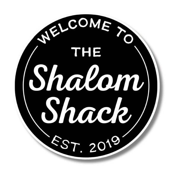 A circular black sign with a white border features WELCOME TO THE Shalom Shack EST. 2019 in a bold, friendly font, mimicking warm beach house decor. This personalized oval custom piece is part of coastal decor offerings.