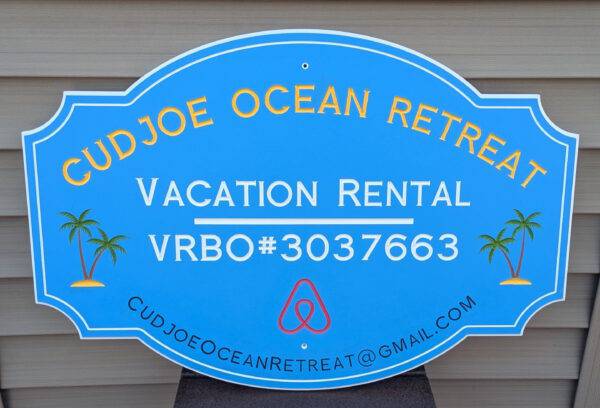 Blue sign displaying Cudjoe Ocean Retreat, Vacation Rental, VRBO#3037663, with a custom palm tree design and email: cudjoeoceanretreat@gmail.com. Perfect for rentals, this bordered sign suits any wood-paneled backdrop. Product: Custom Signs for Homes & Rentals, VRBO, STR.