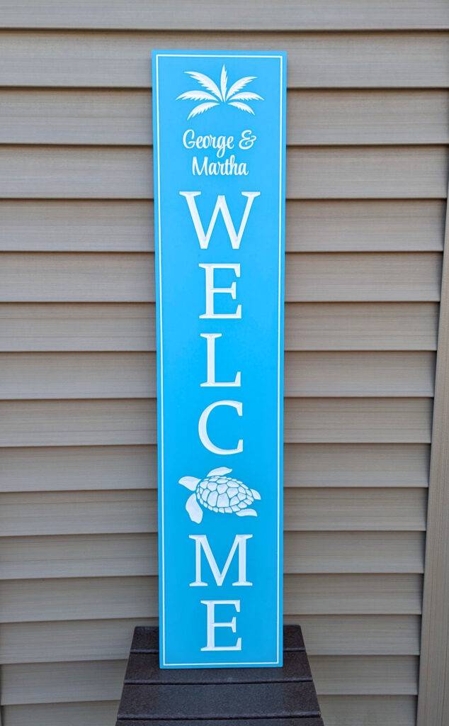 A personalized blue vertical welcome sign, George & Martha WELCOME, features palm trees and a turtle on durable PVC with horizontal beige siding, perfect for a coastal decor.