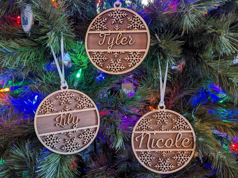 Three wooden ornaments hanging on a christmas tree.