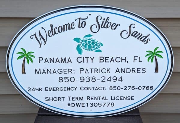 A Custom Sign for rentals reads Welcome to Silver Sands with a turtle and palm trees in Panama City Beach, FL. Managed by Patrick Andres. Contact via phone numbers. Short-term rental license #DWE1305779.