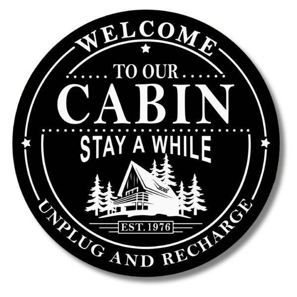 Custom Carved Round PVC Cabin Sign featuring a black circular design with Welcome to Our Cabin, Stay A While, Unplug and Recharge around an illustration of an A-frame cabin among trees. Established 1976 is displayed at the bottom.