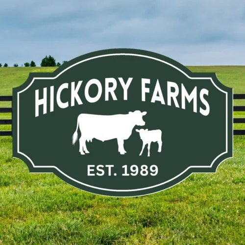 A green sign with white text reading Hickory Farms Est. 1989 and cow silhouettes stands in a grassy field, inspiring the Personalized Custom Carved Farm Sign and Custom Carved Ranch Sign.